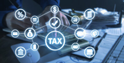 Gestão tributária digital - ícone central de “TAX” conectado a símbolos de finanças, impostos, calculadora e análise de dados sobre mesa de trabalho.