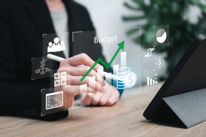 Profissional analisando orçamento em interface digital com gráficos financeiros, ícones de gestão, aumento de receita e planejamento corporativo.